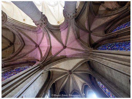 Blick auf ein farbenfrohes gewölbtes Kirchendach mit gotischer Architektur.