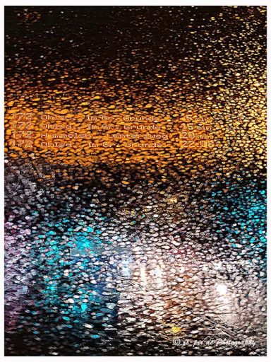 Farbige Lichtreflexionen auf einer nassen Oberfläche, orange und blau dominierend.