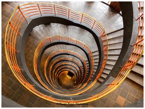 Schwungvolle Treppe mit spiralförmigem Geländer in warmen Farben.
